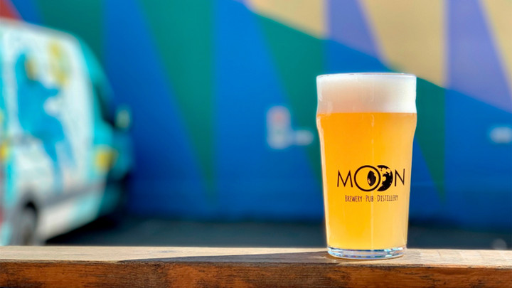 Glass of beer in front of a blurred wall mural.