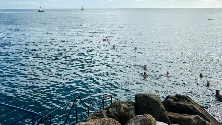 Swimmers swimming in the ocean off the coast of Ireland.