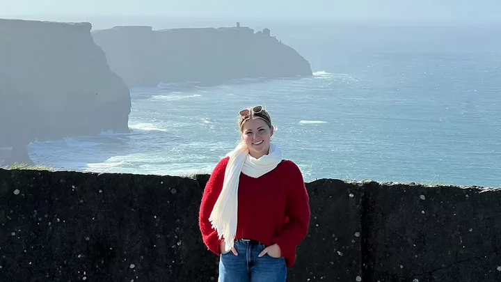 Nina Simons standing in front of a rock wall off the coast of Ireland.