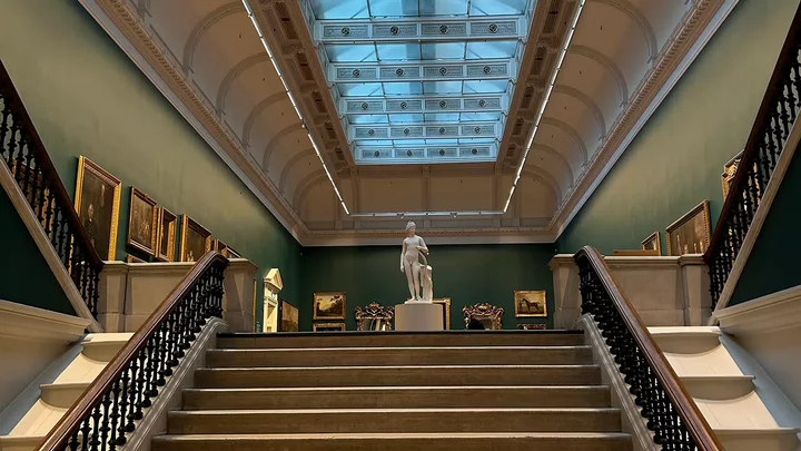 A statue standing up the top of the stairs of the National Gallery in Dublin, Ireland.