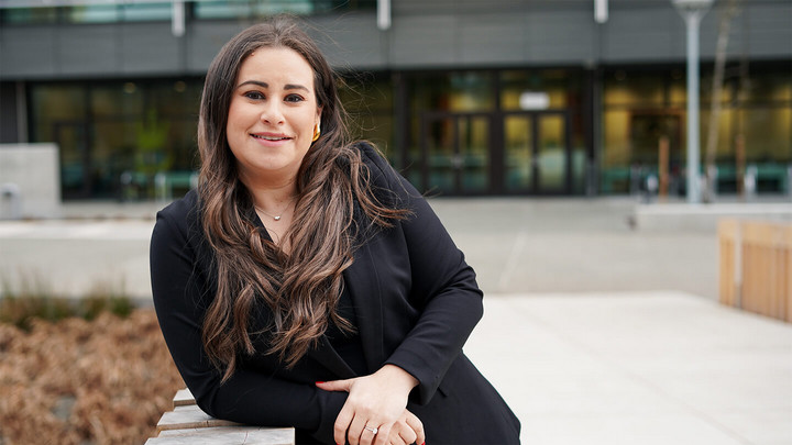 Woman leans against a railing outside of a building.