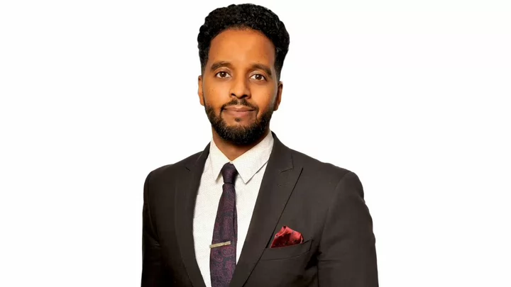 A man with a beard wearing a suit jacket, dress shirt and tie. 