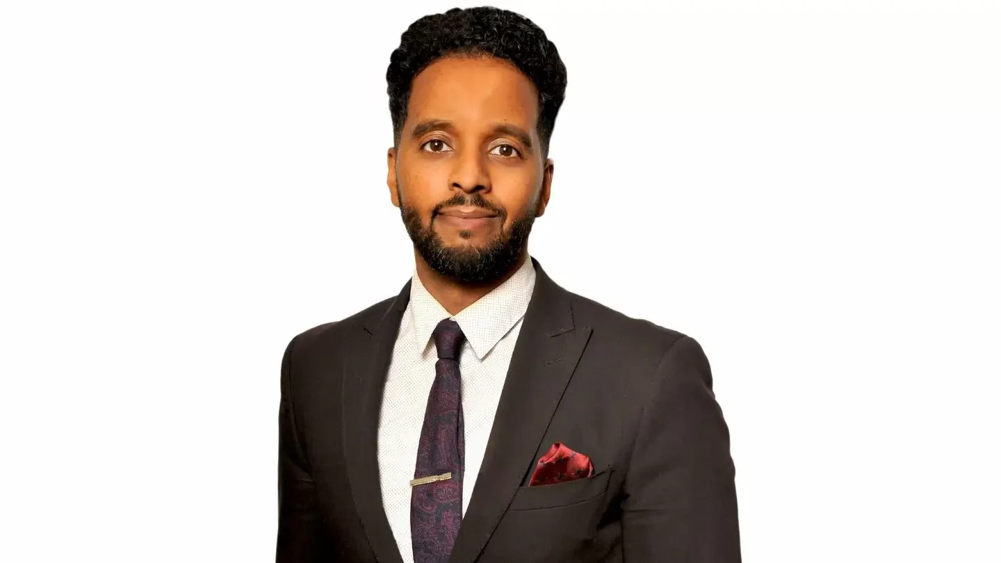 A man with a beard wearing a suit jacket, dress shirt and tie. 