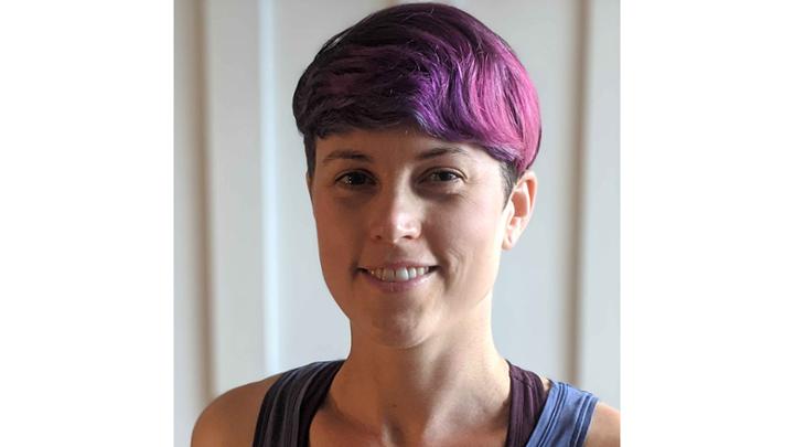 Woman smiling with purple hair.