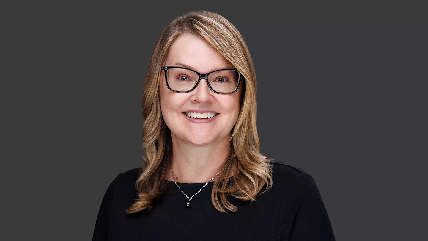 Woman with shoulder length hair and glasses smiling.