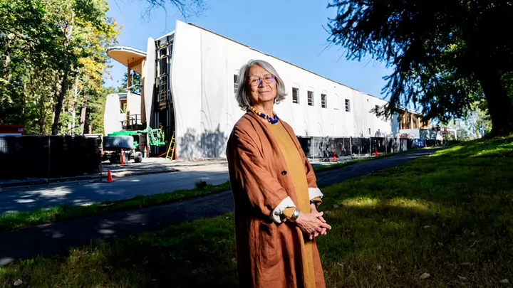 A woman with glasses standing in front of a building under construction.