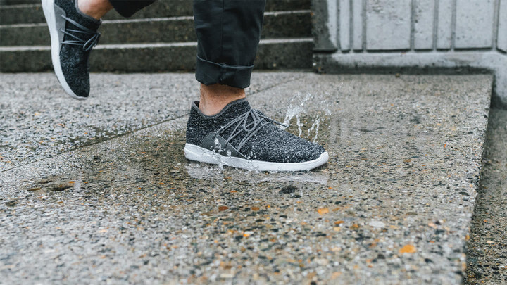 A shoe stepping in a puddle on a sidewalk..