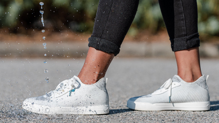 Water splashing up around a white sneaker.