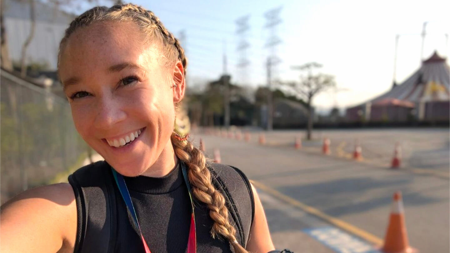 Woman with lanyard around her neck smiling.