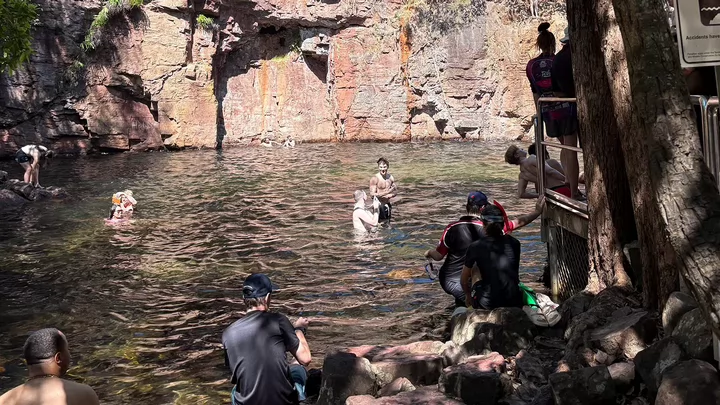 People swimming in a body of water surrounded by rock walls. 