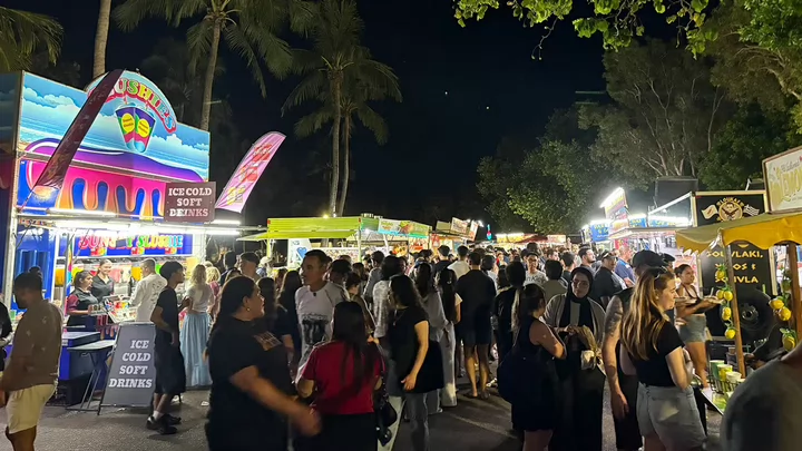 People walking around a crowded night market.