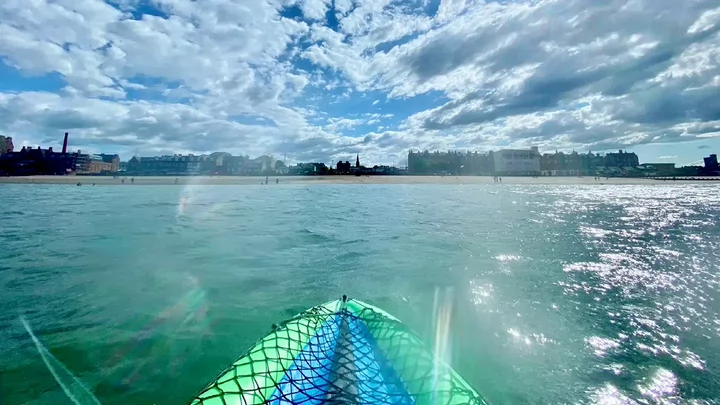 View of a city beach from a kayak floating in the water.