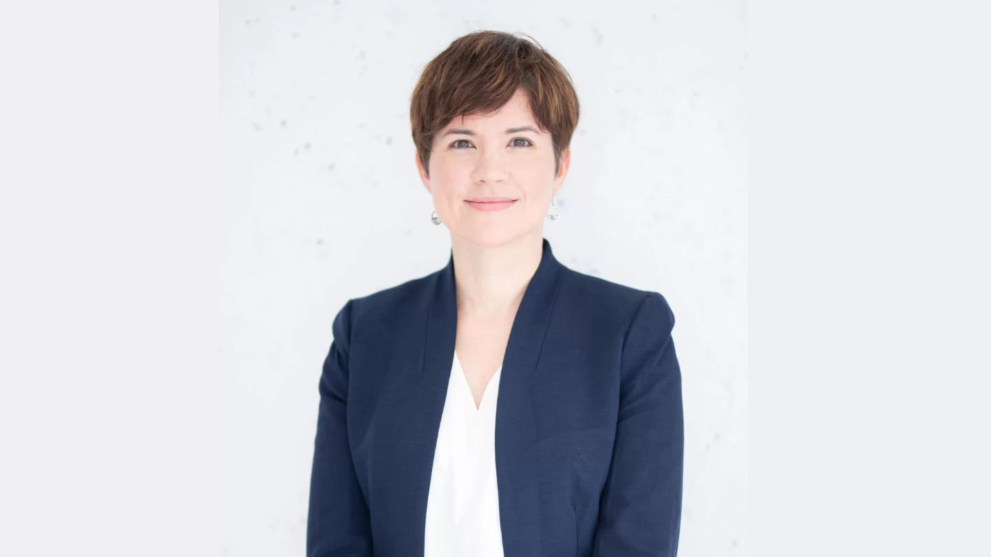 Woman with short hair and wearing a blazer smiling. 