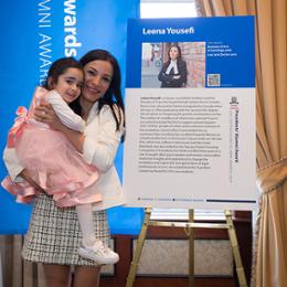 Woman holding child in front of poster board