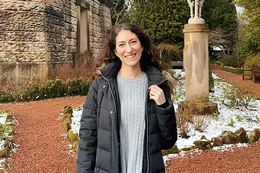 Woman wearing a parka and smiling outside of a castle.