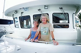 A man and a woman standing on the deck of a yacht.
