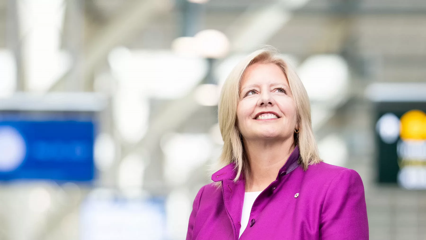 Woman smiling while looking upwards in an airport.