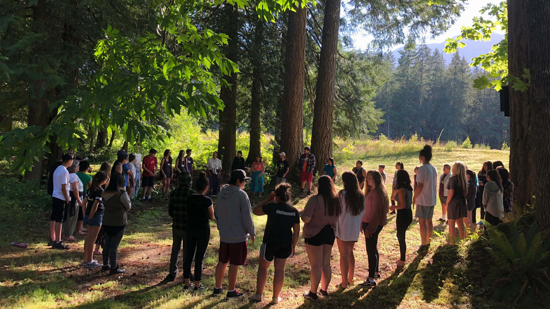 Group of people standing in a circle in the forest. 