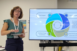 A woman with glasses delivering a Power Point presentation.