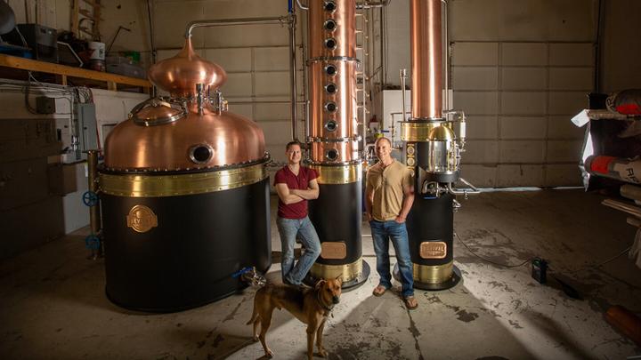 Two men with a dog standing in a distillery