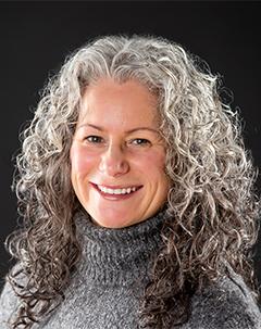 Woman wearing grey sweater smiling. 