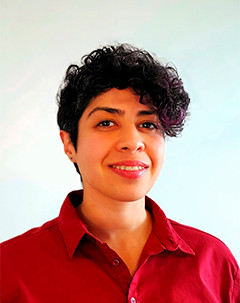 Person with dark curly hair and red button up shirt.