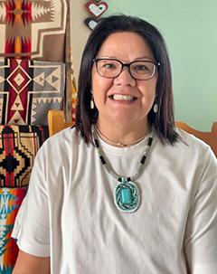 Woman wearing turquoise necklace smiling.