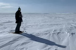 Man wearing snow gear and snow shoes on a snowy landscape.