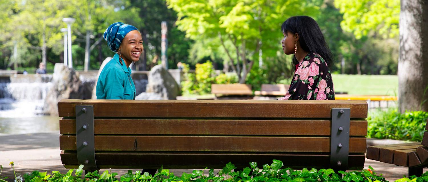 Two UVic students on a bench by the UVic fountain