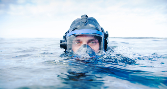 Male student in SCUBA gear emerging from the water