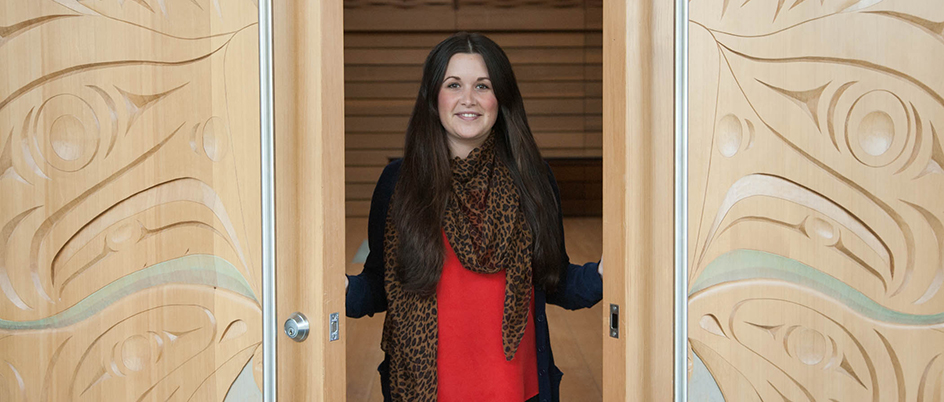 Woman opening the doors of UVic's First Peoples House