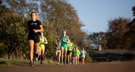 Eight women running in a line, photographed from the front. 