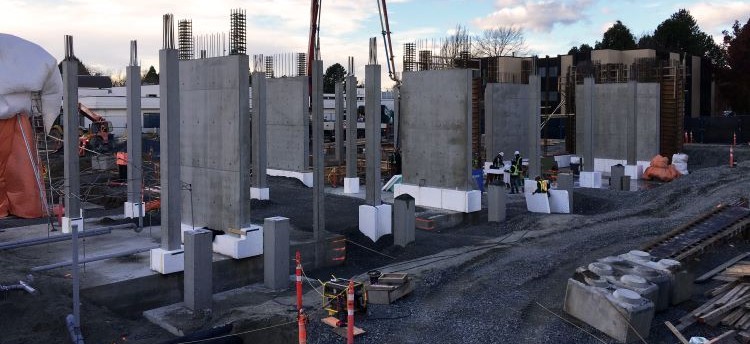 Construction site with vertical concrete structures sitting on top of a concrete foundation.
