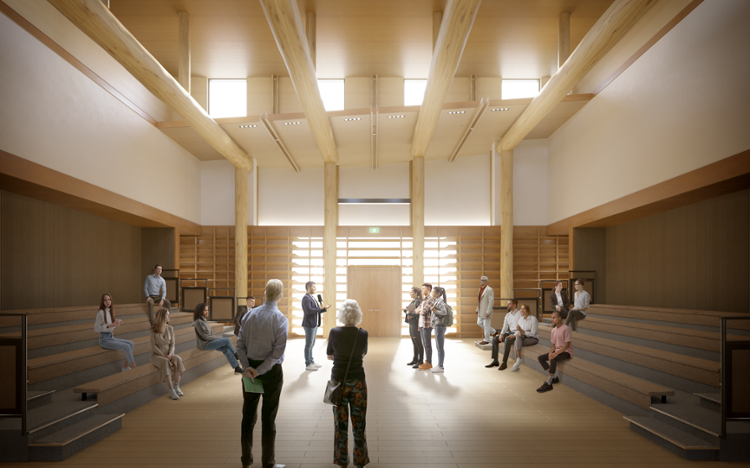 A larger group of people gather in an open designed room with lots of sunlight