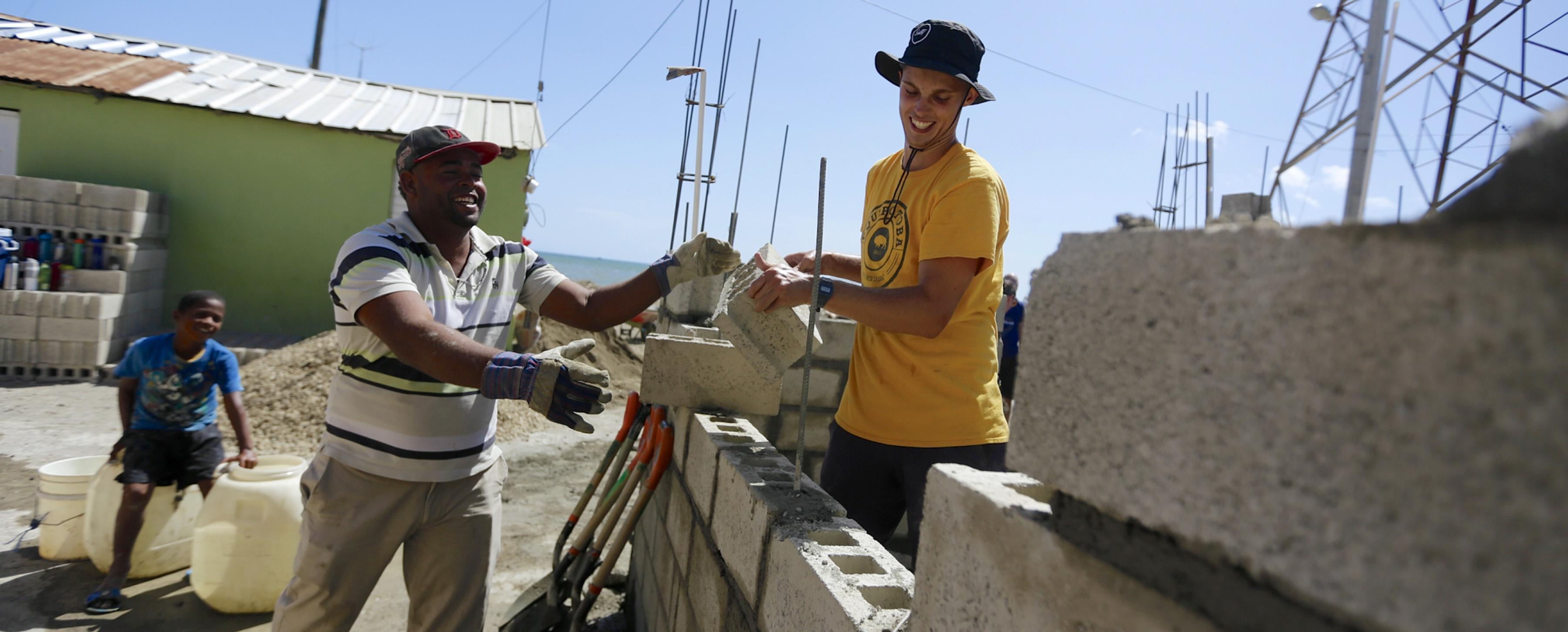 student and helper laying bricks