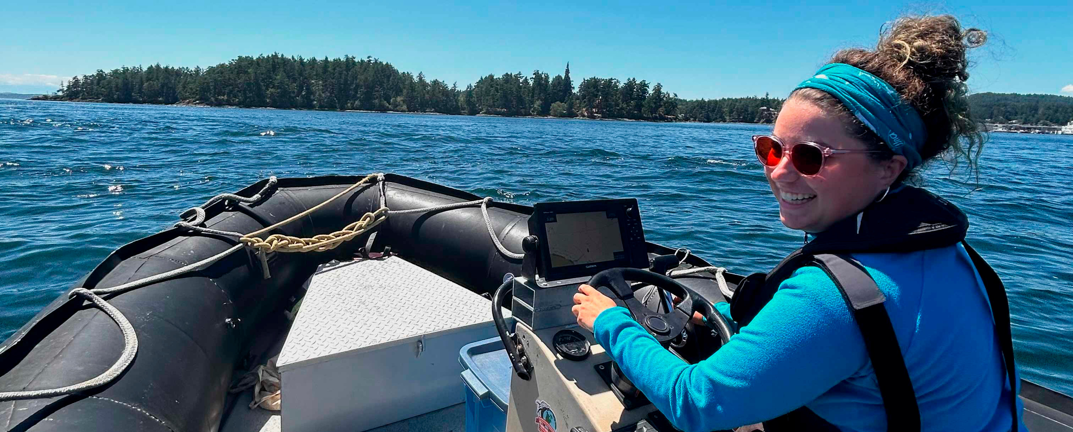 A student wearing overalls and a blue shift rides on a speed boat.