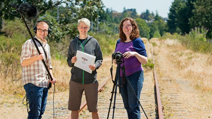 three students shooting video on rail track