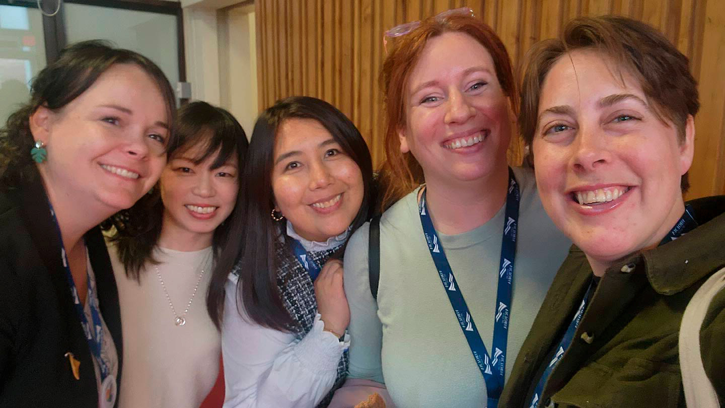 Five people pose for a photo and smile at the camera.
