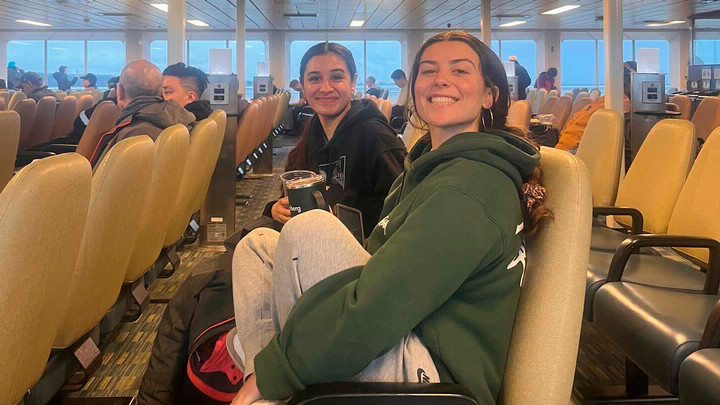 Two people sit on seats on a ferry boat.