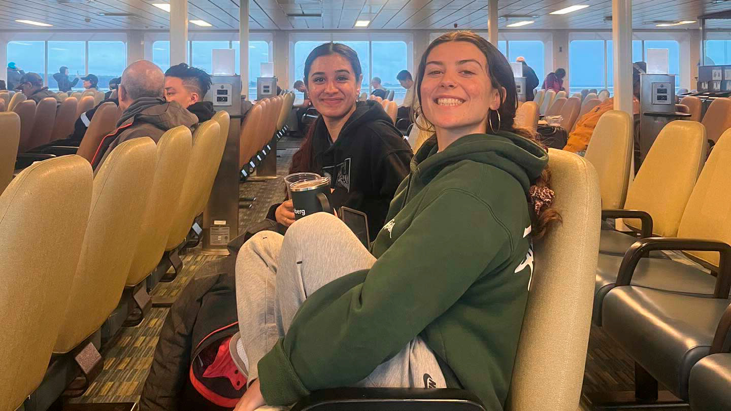 Two people sit on seats on a ferry boat.
