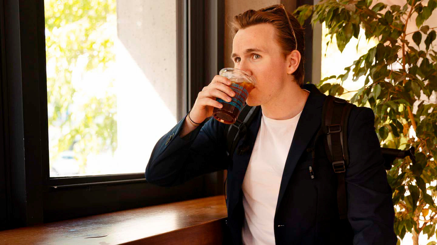 A man sits at a counter and drinks a soft drink.