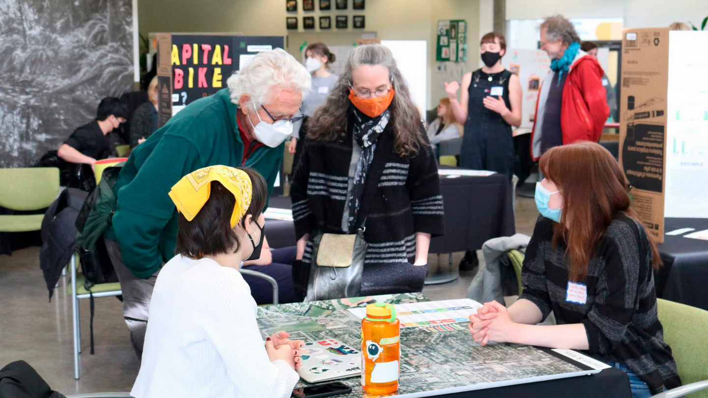 A group of faculty, students and community members discuss projects.