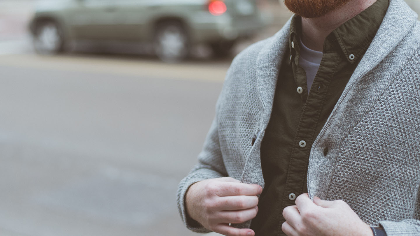 A person buttons up their sweater on the way to a job interview.