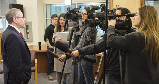 Dr. Aaron Devor being interviewed by members of the media with video cameras