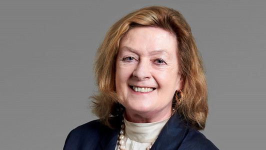 Photo of smiling woman with blondish red hair and a navy blue blazer