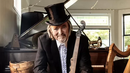Photo of man with top hat sitting in front of a piano