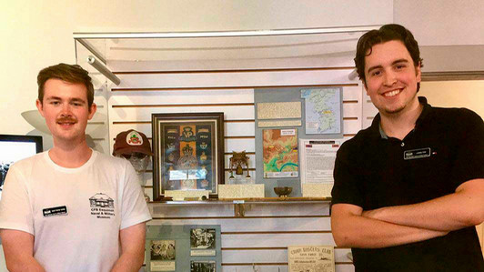 Two students stand in front of a museum display.