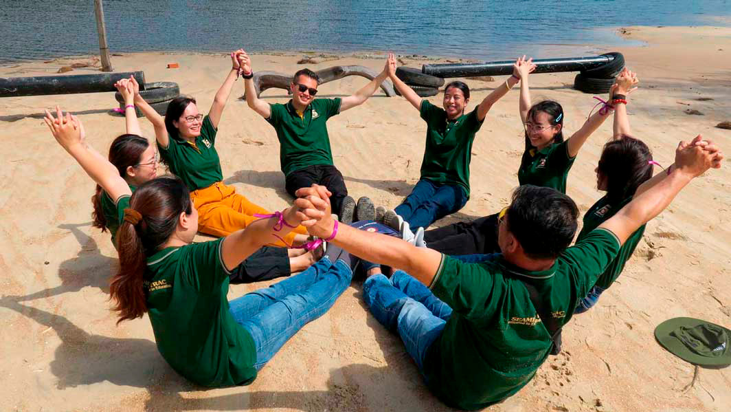 People sit on a bit with their legs together in a circle.