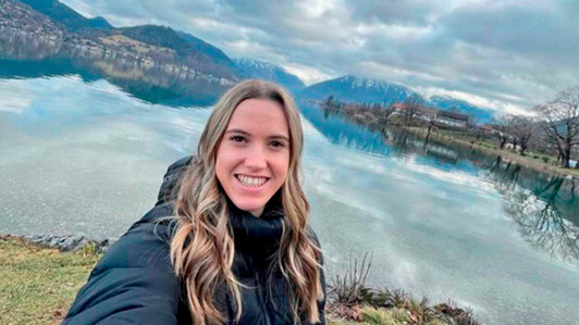A student smiles in front of a lake.