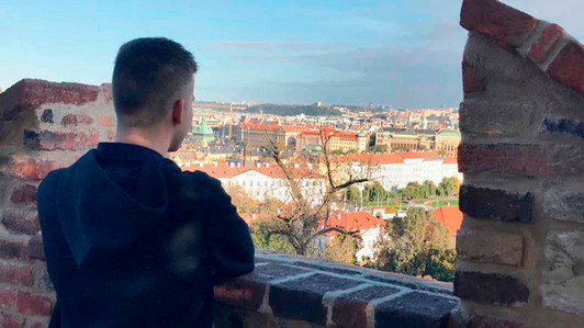A student stands looking over a city.
